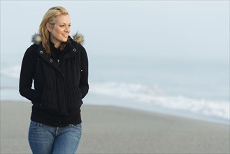 Caucasian woman wearing jacket on beach