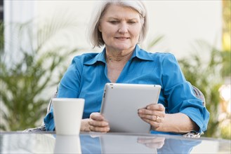 Caucasian older woman using digital tablet in backyard