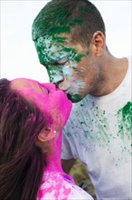 Caucasian couple splattered with paint powder kissing