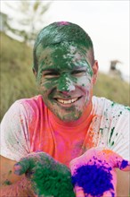 Caucasian man splattered with paint powder showing hands
