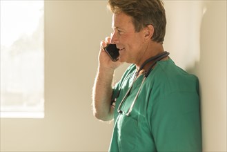 Caucasian nurse talking on cell phone near window