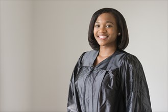 Mixed race graduate smiling in graduation robe