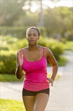Mixed race woman jogging on suburban sidewalk