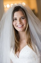 Caucasian bride smiling in wedding gown and veil