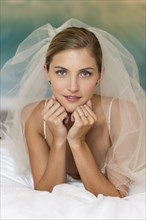 Caucasian bride in wedding veil leaning on elbows
