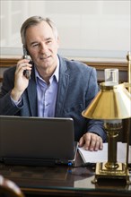 Caucasian businessman talking on cell phone at desk
