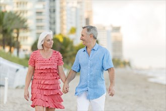Older Caucasian couple walking on beach