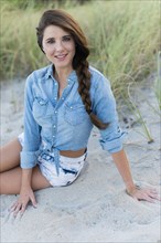 Hispanic woman sitting on beach