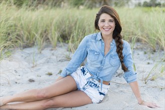 Hispanic woman sitting on beach