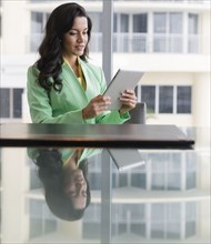 Hispanic businesswoman using digital tablet at conference table