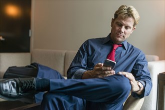 Caucasian businessman using cell phone in office lobby