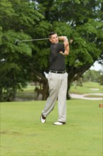 Caucasian man swinging club on golf course