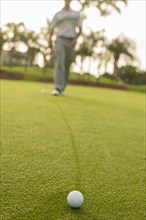 Caucasian man walking to golf ball on golf course green