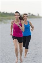 Caucasian women running on beach