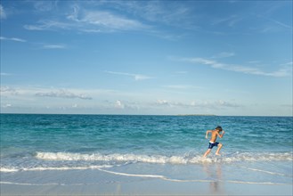 Hispanic boy running on beach