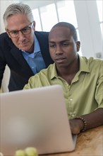 Businessmen using laptop at desk