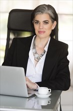 Caucasian businesswoman using laptop in office