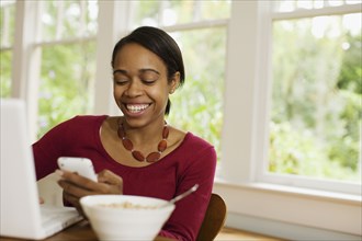 African woman reading text message at breakfast