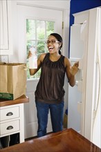 African woman unloading groceries in kitchen