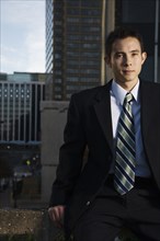 Mixed race businessman sitting on urban rooftop