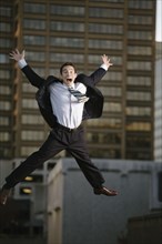 Excited mixed race businessman jumping in mid-air