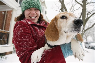 Caucasian woman holding dog in snow