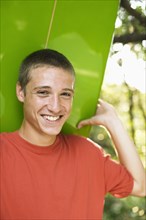 Close up of Caucasian teenage boy smiling and holding surfboard