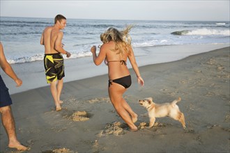 Teenagers and puppy running on beach