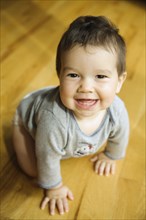 Smiling mixed race boy crawling on floor