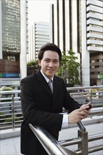 Asian businessman text messaging on cell phone outdoors
