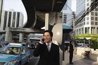 Asian businessman talking on cell phone outdoors