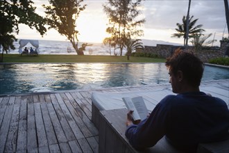 Caucasian man reading at poolside
