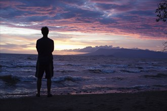 Caucasian man standing on beach viewing sunset