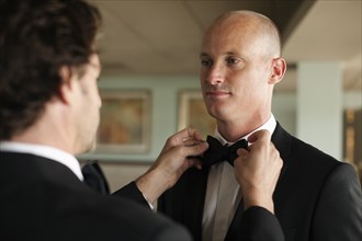 Man adjusting groom's bow tie