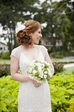 Smiling Caucasian bride holding wedding bouquet