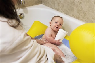 Caucasian mother bathing baby boy