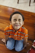 Mixed race boy making a face on floor