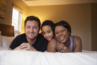 Smiling family laying on bed