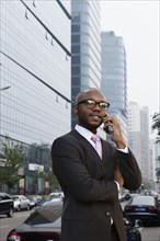 Black businessman talking on cell phone on city street