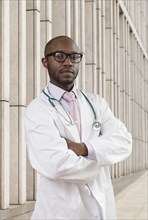 Black doctor standing on city street