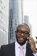 Black businessman talking on cell phone on city street