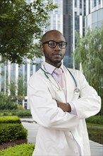 Black doctor standing in urban park