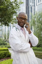Black doctor talking on cell phone in urban park