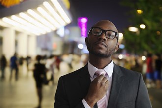 Black businessman adjusting tie on city street