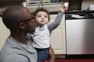 Father holding baby in kitchen