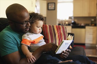 Father reading to baby on sofa