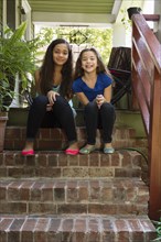 Mixed race sisters sitting on steps