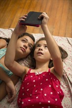 Mixed race sisters using digital tablet on bed