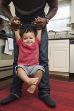 Father holding toddler son in kitchen