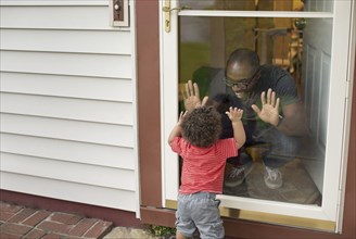 Father and toddler son playing at screen door